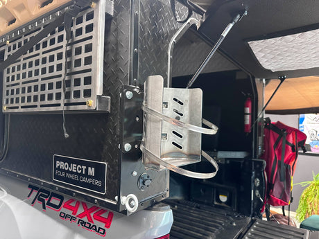 Side view of a propane bracket mounted to the back of a truck bed camper.