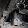 Close-up of mechanical components under a vehicle, showing rust and wear.