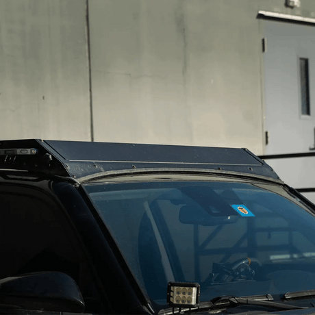 Car with a roof rack and windshield wipers against a concrete wall.
