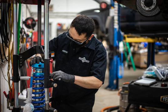 Mechanic working on a vehicle suspension system in a garage.