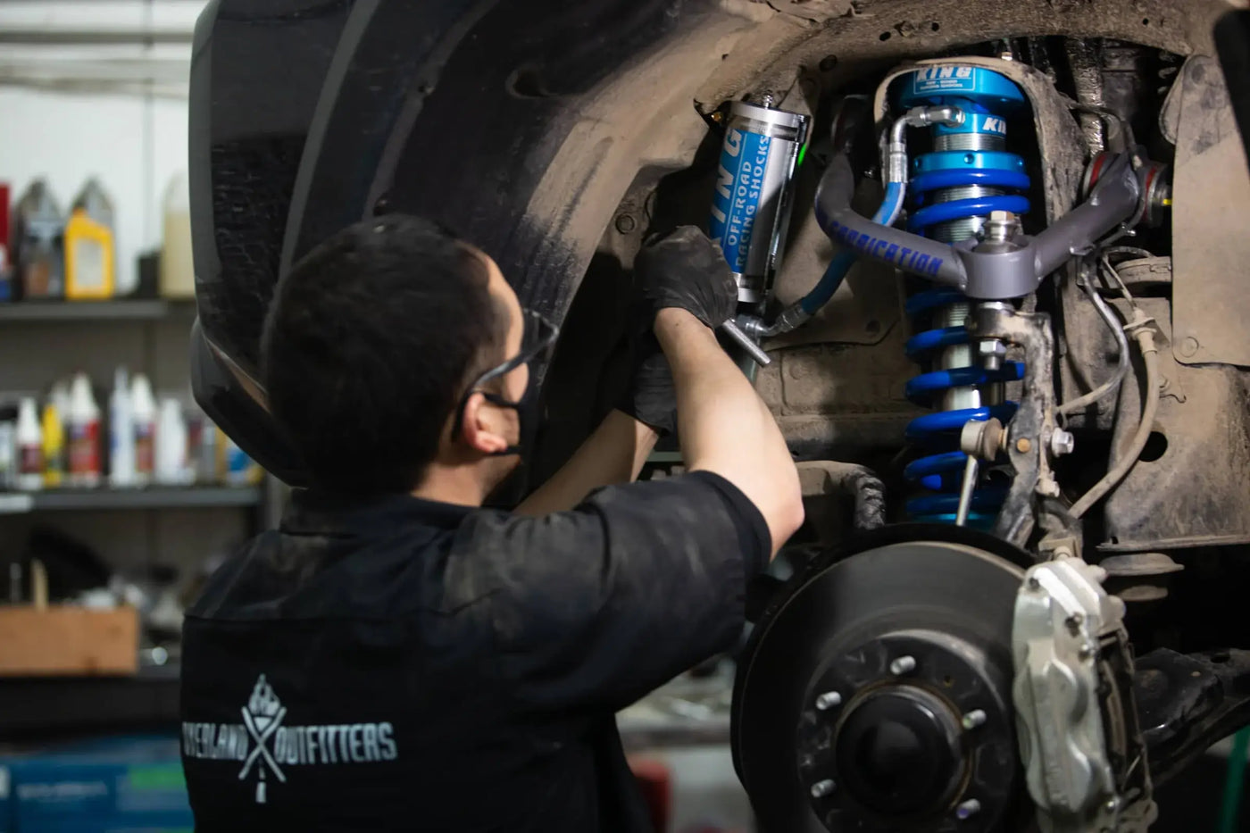 Mechanic installing suspension parts on a truck on a lift in a garage