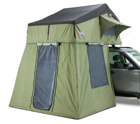 A green tent and annex extension with a black top designed for rooftop attachment, pictured with a vehicle.