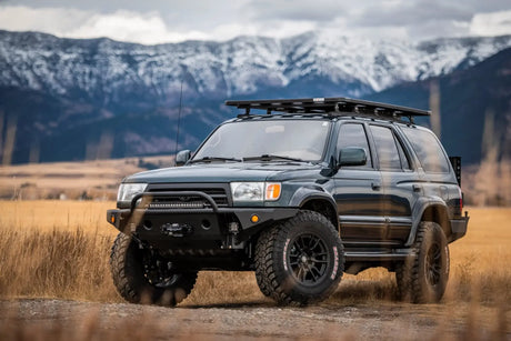 Black SUV with roof rack in a field with mountains in the background