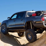 Black off-road truck with large tires rock crawling over rugged terrain