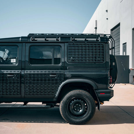 Black off-road vehicle with a textured back panel on a concrete surface.