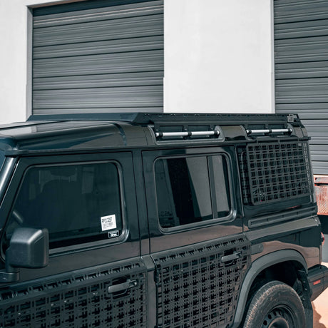 Black SUV with a textured front bumper parked in front of a building with gray shutters.