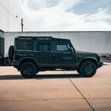 Black off-road vehicle parked on a concrete surface with a building in the background